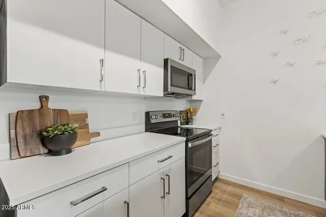 a kitchen with stainless steel appliances a sink a counter space and a view of living room