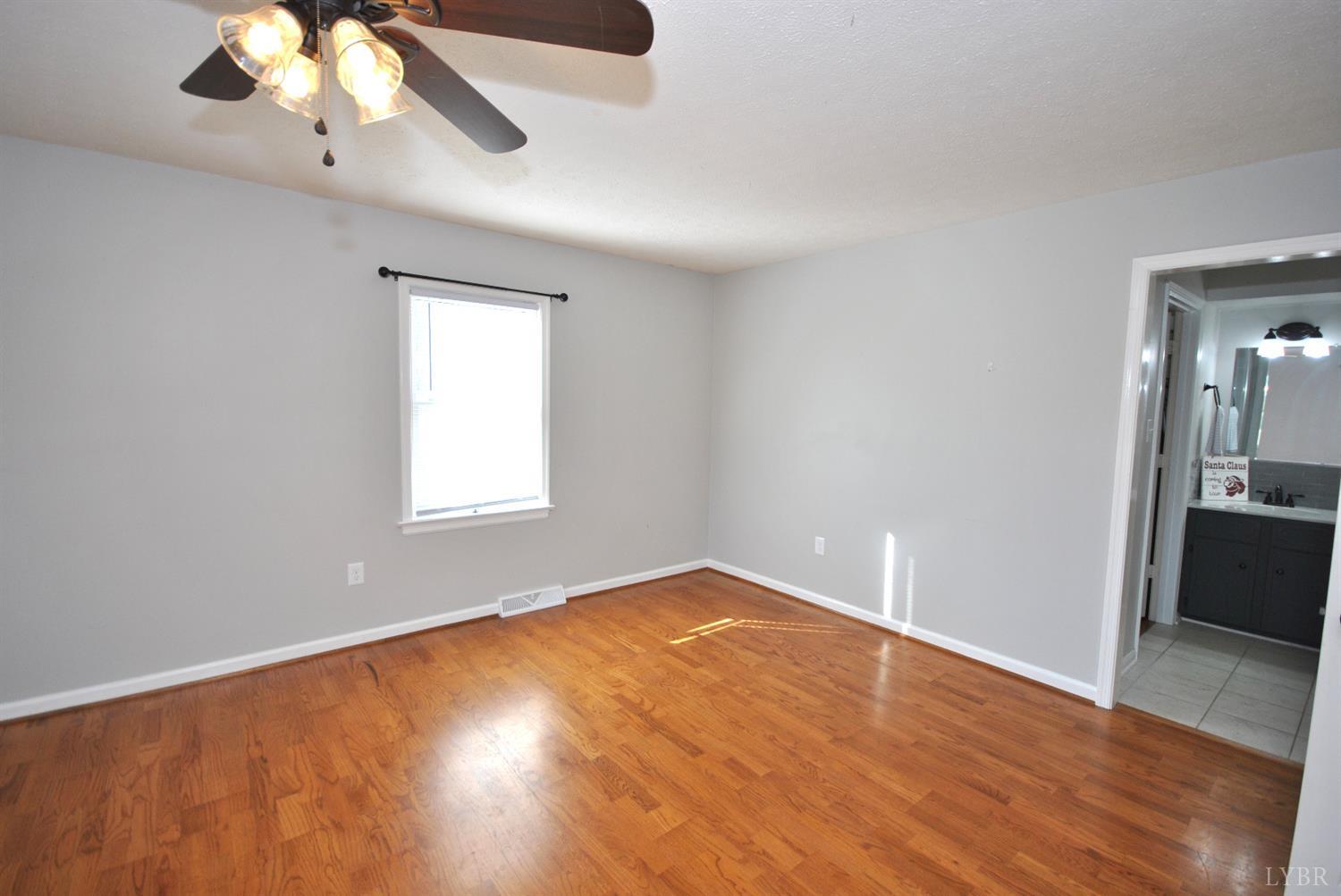 3350 Roaring Run Road Goode, VA 24556 - Photo 41 of 90 an empty room with wooden floor chandelier fan and windows