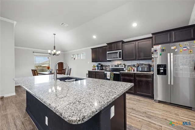 a kitchen with stainless steel appliances granite countertop a sink refrigerator and microwave