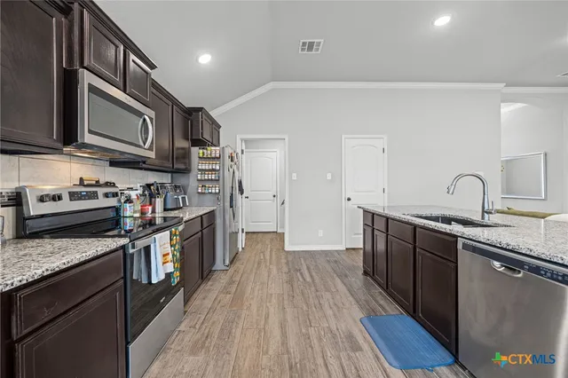 a kitchen with stainless steel appliances granite countertop a stove a sink and a refrigerator