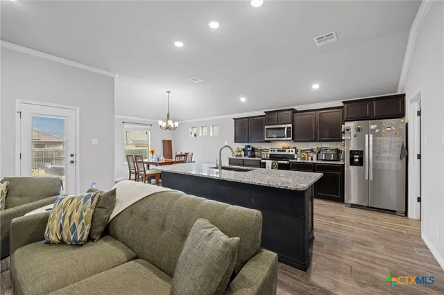 a living room with stainless steel appliances kitchen island granite countertop furniture a refrigerator a sink a kitchen island and couches