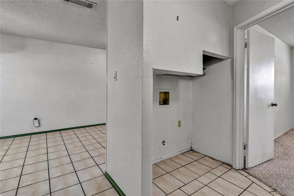 210 Slaughter Street Arlington, TX 76011 - Photo 11 of 33 Laundry area with a textured ceiling, washer hookup, light colored carpet, light tile patterned flooring, and a textured wall