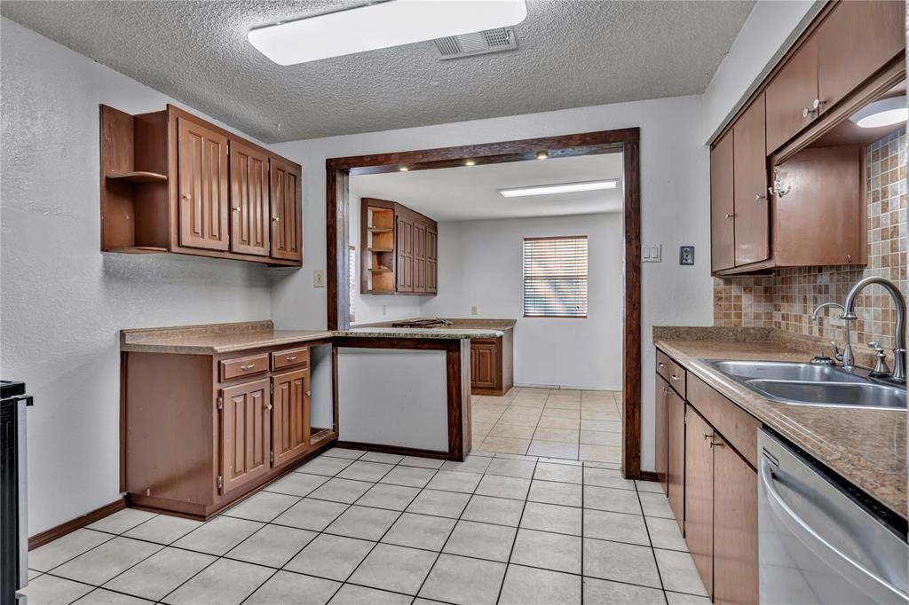 210 Slaughter Street Arlington, TX 76011 - Photo 13 of 33 Kitchen with dishwasher, a textured ceiling, a peninsula, light tile patterned floors, and open shelves