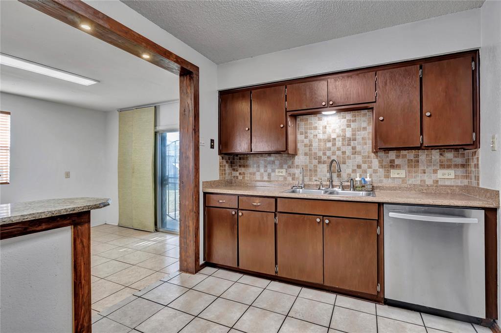 210 Slaughter Street Arlington, TX 76011 - Photo 15 of 33 Kitchen with stainless steel dishwasher, tasteful backsplash, light tile patterned floors, and a textured ceiling