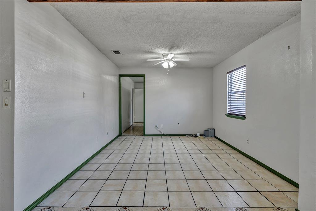 210 Slaughter Street Arlington, TX 76011 - Photo 19 of 33 Spare room with a textured ceiling, a ceiling fan, and light tile patterned floors
