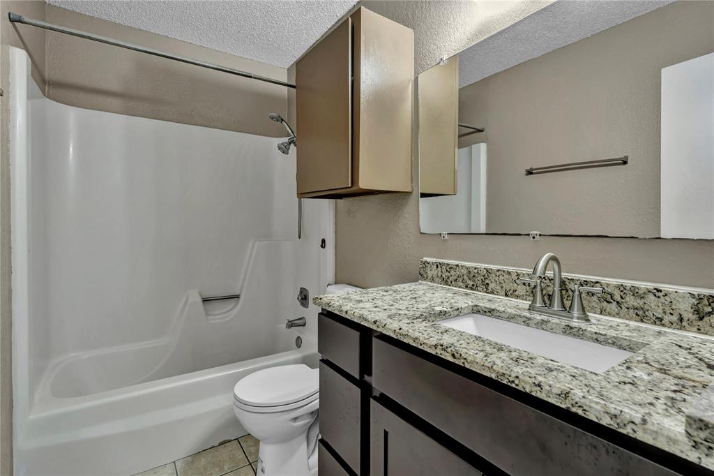 210 Slaughter Street Arlington, TX 76011 - Photo 29 of 33 Full bath featuring bathtub / shower combination, vanity, a textured ceiling, and light tile patterned floors
