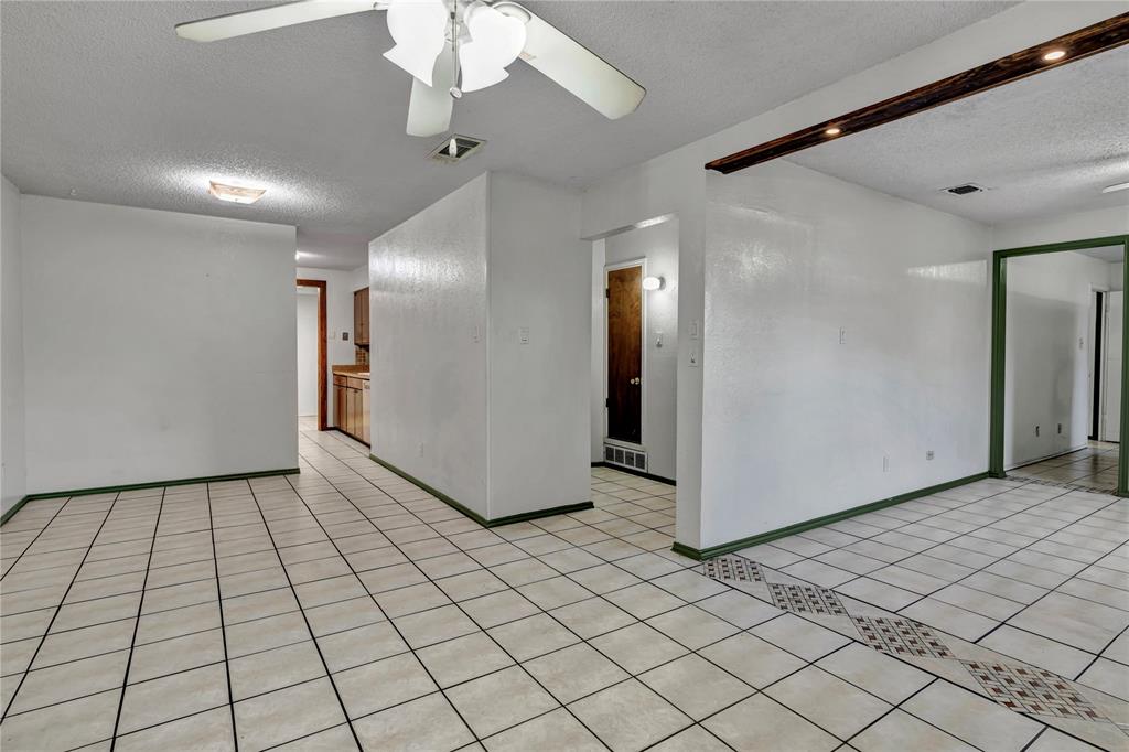 210 Slaughter Street Arlington, TX 76011 - Photo 8 of 33 Spare room featuring a textured ceiling, ceiling fan, and light tile patterned floors
