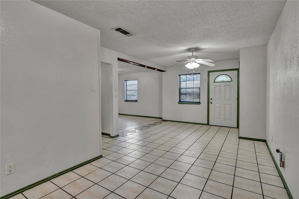 210 Slaughter Street Arlington, TX 76011 - Photo 9 of 33 Spare room with light tile patterned flooring, a textured ceiling, and a ceiling fan