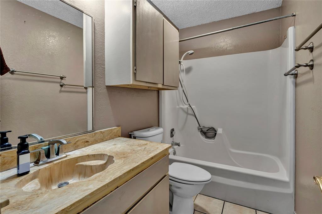 210 Slaughter Street Arlington, TX 76011 - Photo 10 of 33 Bathroom with a textured ceiling, shower / bath combination, vanity, and tile patterned flooring