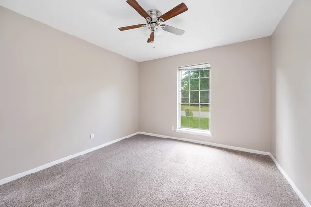 an empty room with a window and a fan