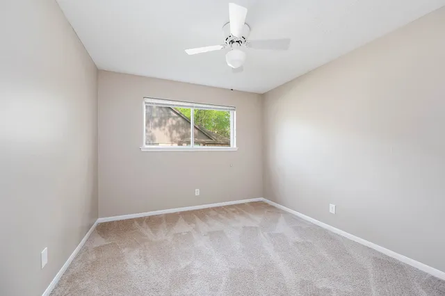 an empty room with windows and ceiling fan