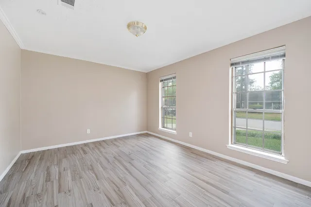 a view of an empty room with wooden floor and a window