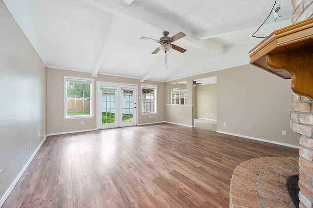 a view of an empty room with wooden floor and a window