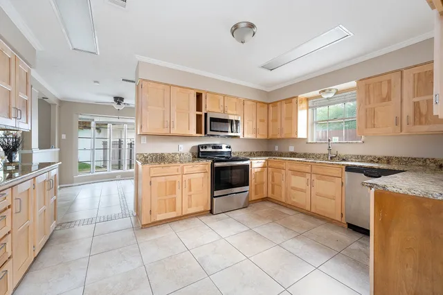 a large kitchen with granite countertop a stove top oven a sink a counter space and cabinets