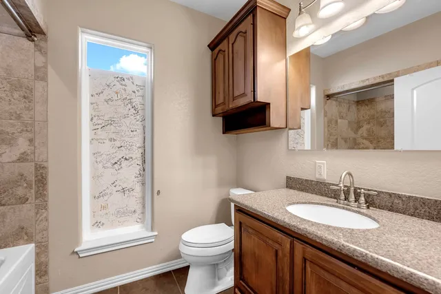 a bathroom with a granite countertop sink toilet and mirror