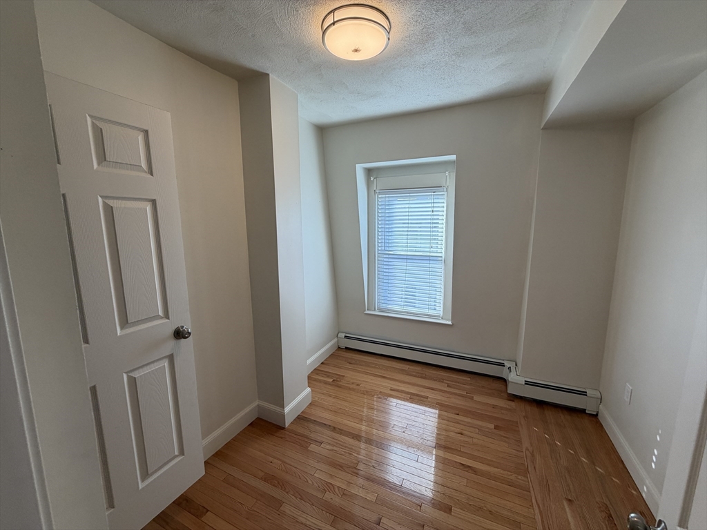 130 West 8th Street, Unit 3 Boston, MA 02127 - Photo 11 of 32 an empty room with wooden floor and windows