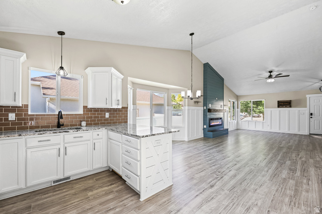 5525 Hampton Way Stansbury Park, UT 84074 - Photo 7 of 35 Open-concept living space featuring vaulted ceilings and wood-finish flooring