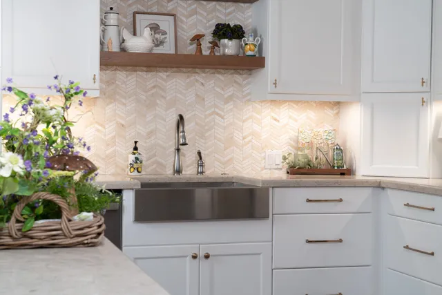 a sink with white cabinets and potted plant
