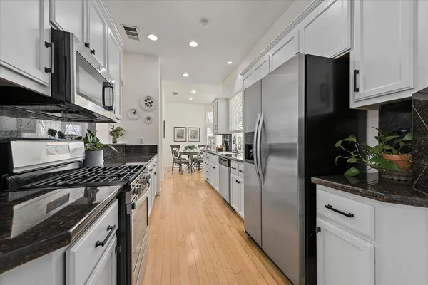 a kitchen with stainless steel appliances a refrigerator a sink a stove and cabinets