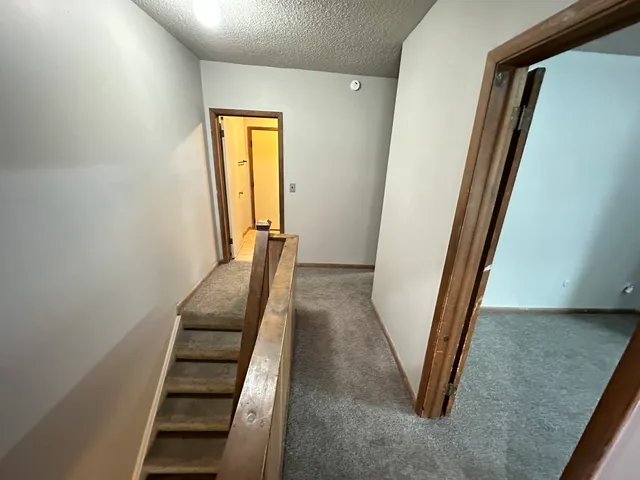 a view of a hallway with wooden floor and stairs