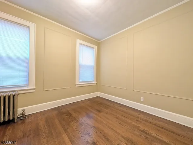 an empty room with wooden floor and windows with curtains