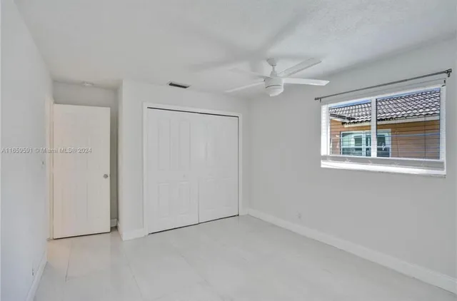 an empty room with a window and a ceiling fan