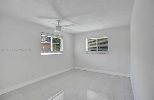 an empty room with a window and a ceiling fan