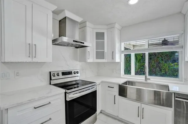 a kitchen with stainless steel appliances white cabinets and a stove top oven
