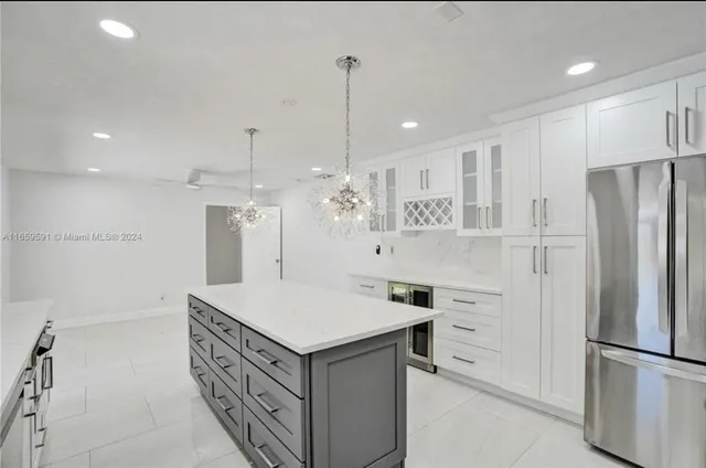 a large white kitchen with kitchen island a sink a stove a refrigerator and white cabinets