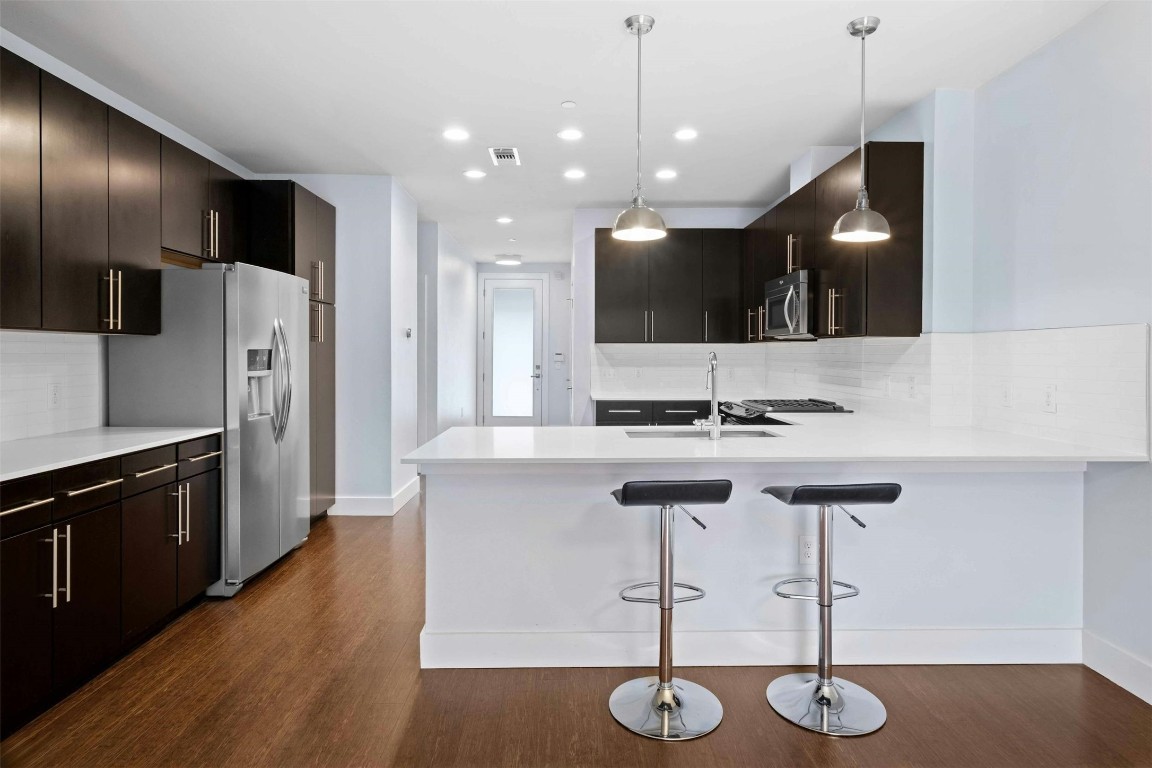 a kitchen with stainless steel appliances kitchen island a sink cabinets and wooden floor