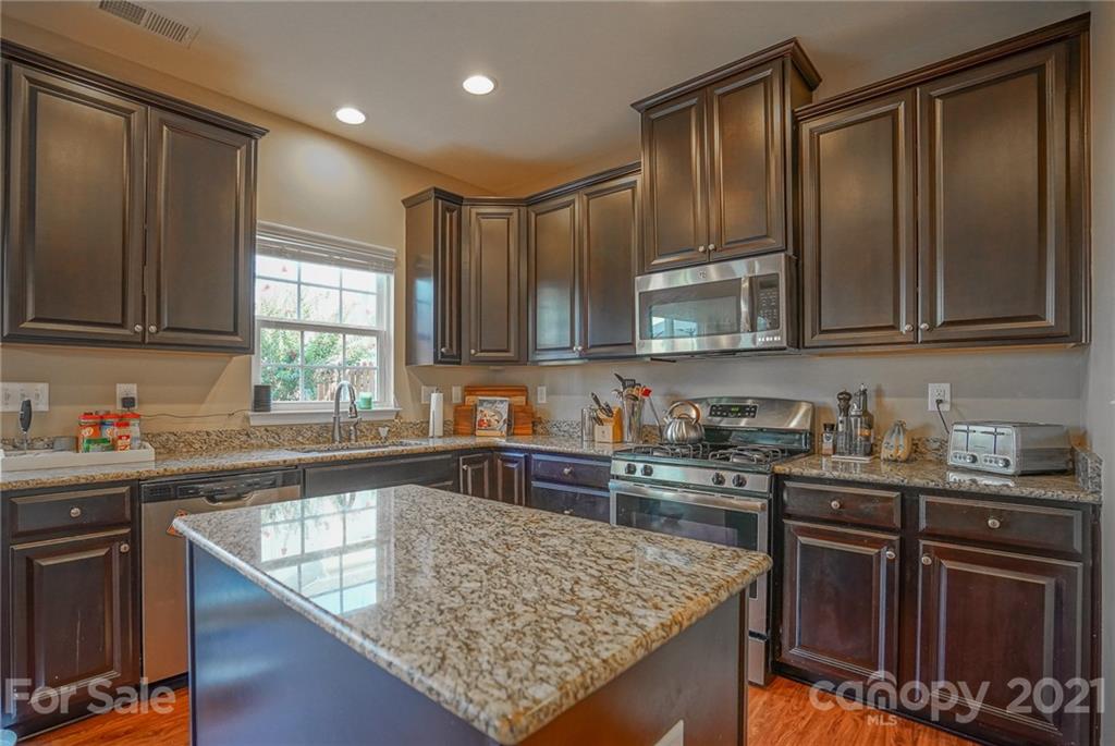 285 Almora Loop Mooresville, NC 28115 - Photo 13 of 45 a kitchen with stainless steel appliances granite countertop wooden cabinets a stove top oven a sink and dishwasher
