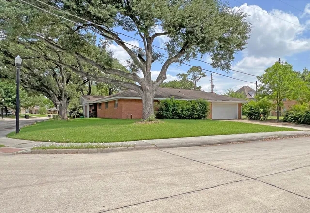 a view of a house with a big yard plants and large trees