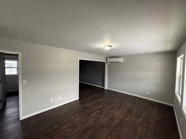a view of an empty room with wooden floor and closet