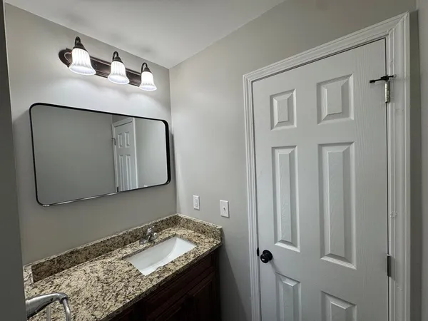 a bathroom with a granite countertop sink and a mirror