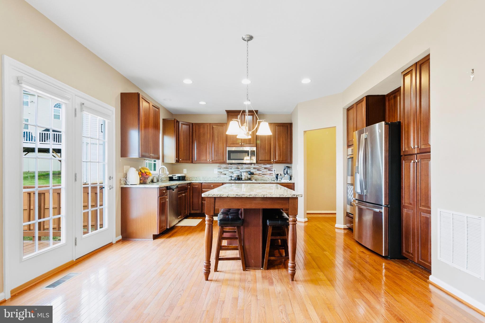 3214 Fledgling Circle Woodbridge, VA 22193 - Photo 15 of 30 a kitchen with stainless steel appliances granite countertop a refrigerator a sink dishwasher a stove and a dining table with wooden floor
