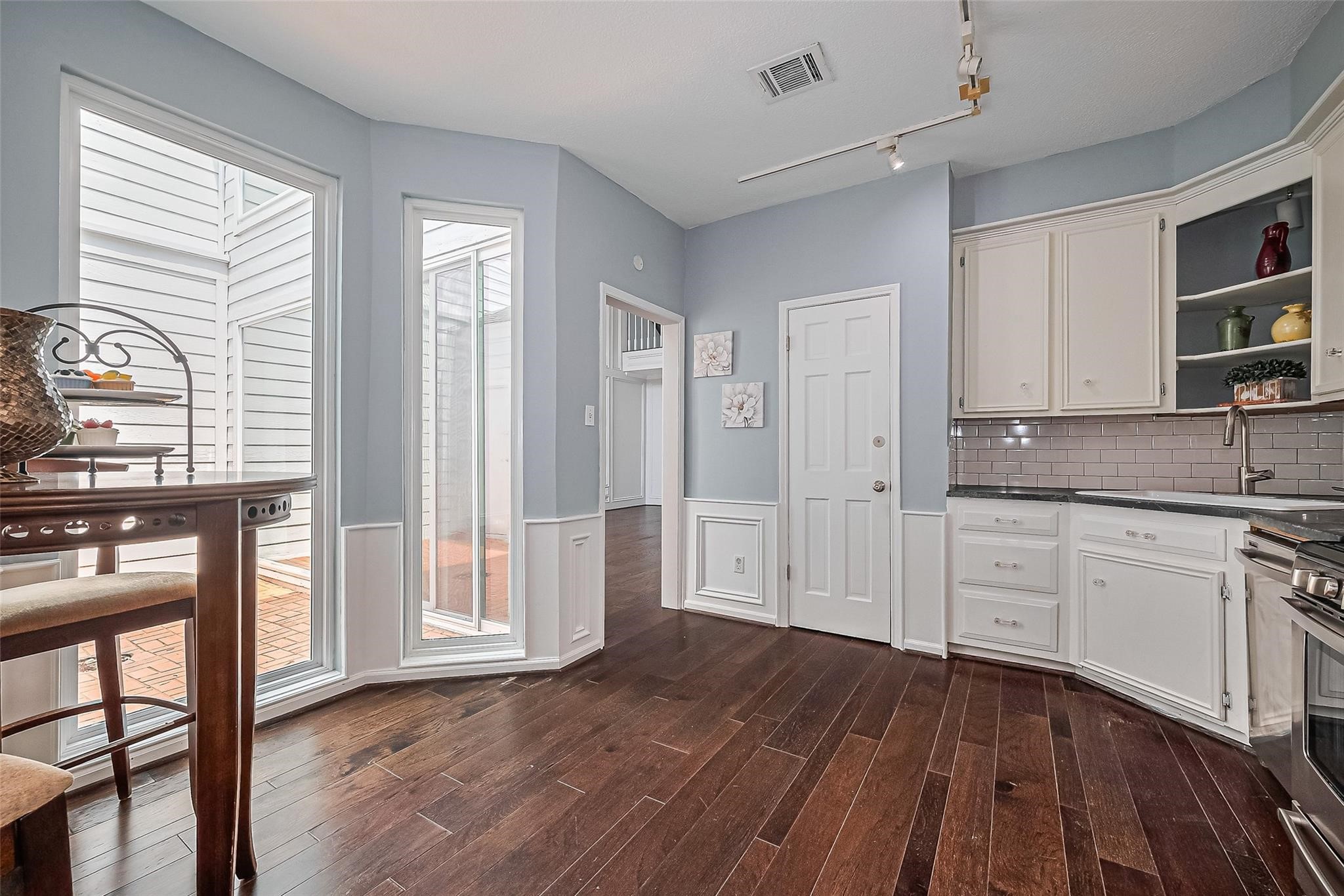 4305 Westheimer Road Houston, TX 77027 - Photo 8 of 25 Bright kitchen with elegant hardwood floors, white cabinetry, and large windows providing abundant natural light.