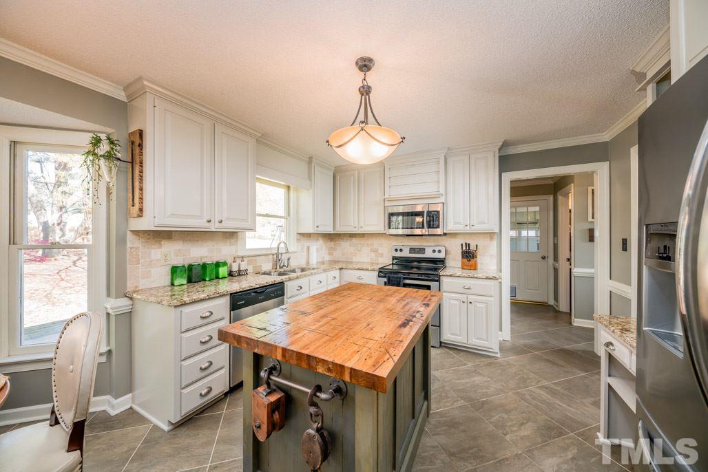 6108 Wolverhampton Drive Raleigh, NC 27603 - Photo 14 of 30 a kitchen with stainless steel appliances a stove sink refrigerator and cabinets