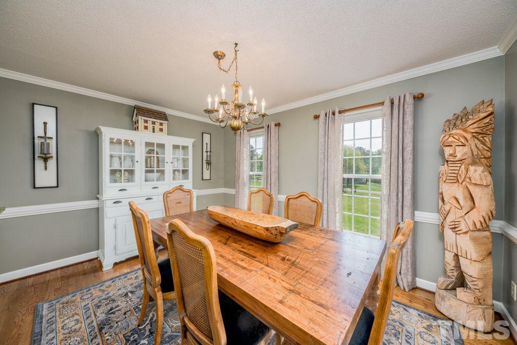 6108 Wolverhampton Drive Raleigh, NC 27603 - Photo 7 of 30 a view of a dining room with furniture a chandelier and wooden floor