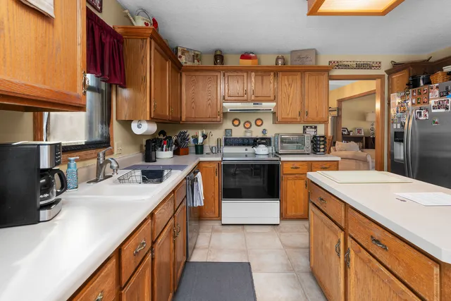 a kitchen with stainless steel appliances kitchen island granite countertop a sink a stove and a refrigerator