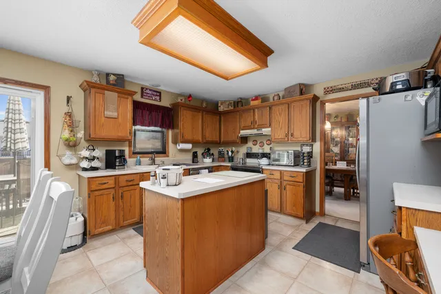 a kitchen with stainless steel appliances kitchen island granite countertop a refrigerator a stove top oven a sink and dishwasher