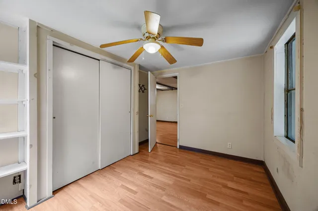 a view of empty room with wooden floor and fan