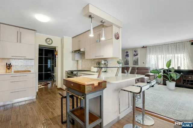 a kitchen with stainless steel appliances a stove a sink cabinets and a wooden floor