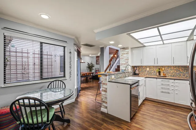 a kitchen with a table chairs wooden cabinets and stainless steel appliances