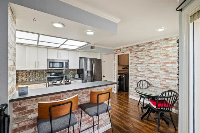 a kitchen with stainless steel appliances kitchen island granite countertop a stove a sink and a refrigerator