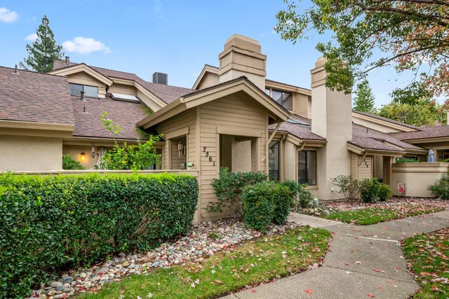 a front view of a house with a yard and potted plants