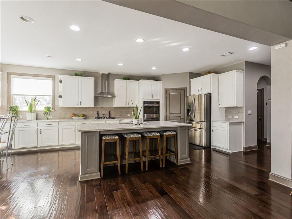 3820 Mabry Ridge Drive Buford, GA 30518 - Photo 4 of 55 a large kitchen with stainless steel appliances granite countertop a stove a sink a refrigerator and white cabinets with wooden floor
