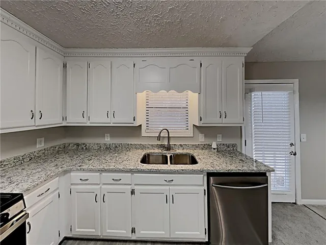 a kitchen with granite countertop white cabinets and sink