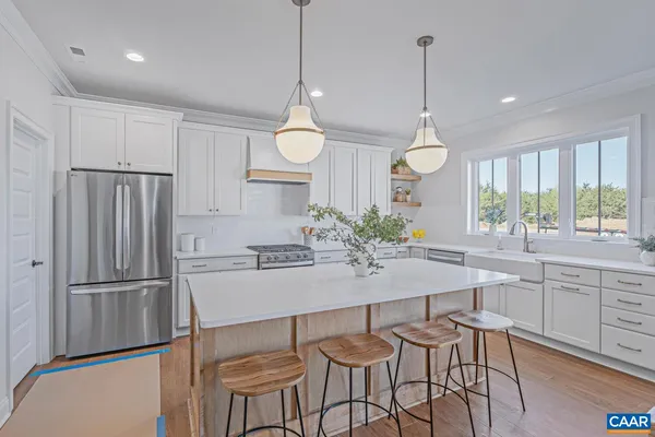 a kitchen with granite countertop a refrigerator a stove a sink and chairs