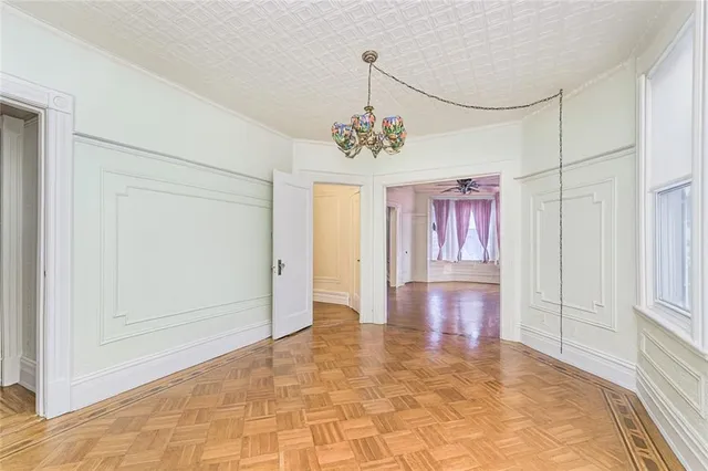 a view of a hallway with wooden floor and a chandelier