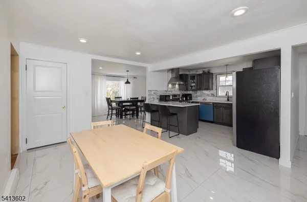 a kitchen with stainless steel appliances kitchen island granite countertop a refrigerator a stove a sink a dining table and chairs